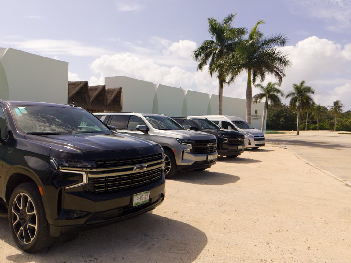 Blue Dreams fleet of private Suburban SUVs and a Van lined up at a Riviera Maya resort entrance