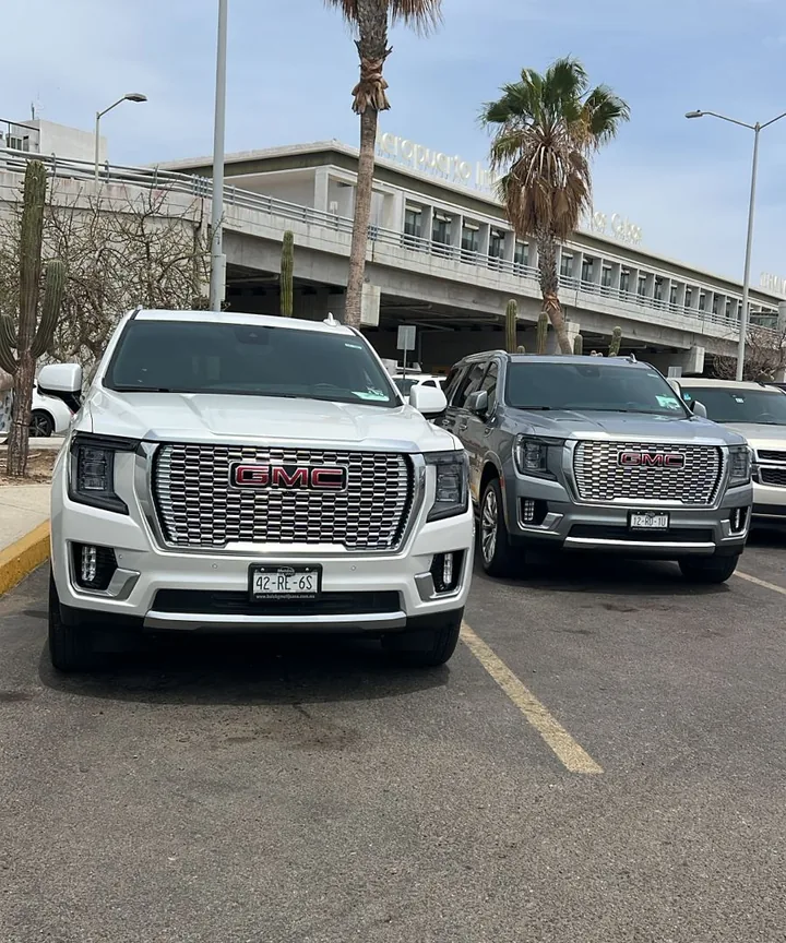 White and gray GMC Yukon Denali SUVs waiting for travelers at Los Cabos International Airport