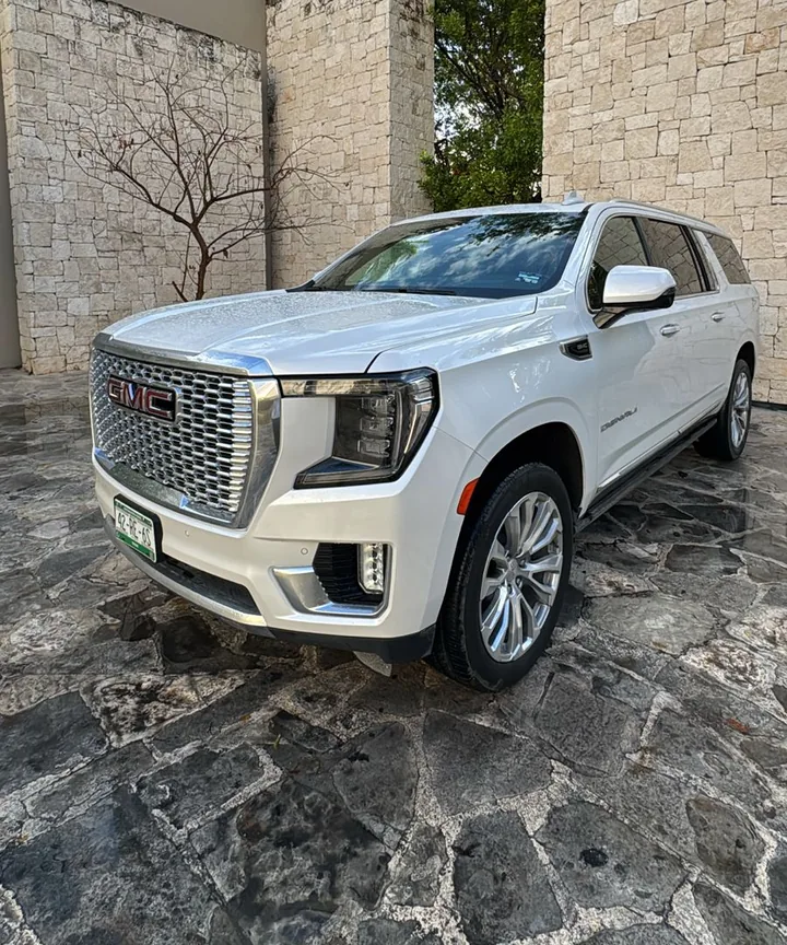 White GMC Yukon Denali for private airport transfers, parked at a stone resort entrance